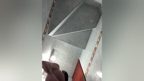 A video of a modern, geometrically designed interior featuring a light gray ceiling with triangular, glass panels and a red wall. The image is taken from a low angle, emphasizing the ceiling's angles and textures.