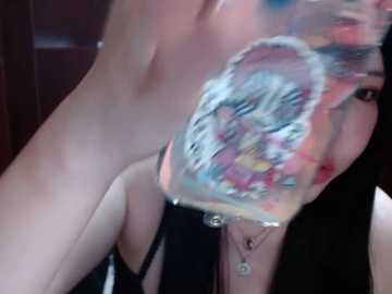 Video of a woman with pale skin and dark hair, partially visible. Her face is covered in colorful, abstract paint, creating a vibrant, artistic effect. She wears a black strapless top and a necklace.