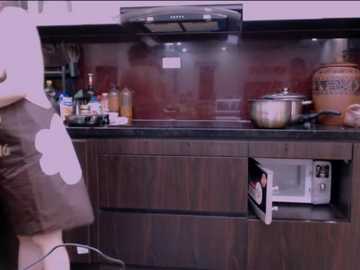 Video of a modern kitchen with a dark wooden countertop, stainless steel appliances, and a black and white apron hanging on a cabinet.