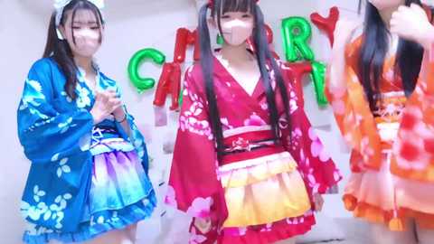 Video of three young women in vibrant Japanese kimonos, smiling and posing in front of a \"CARRY\" backdrop.