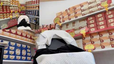 Video of a supermarket aisle displaying colorful, neatly stacked boxes of instant noodles, with yellow price tags and a white aproned worker in the background.