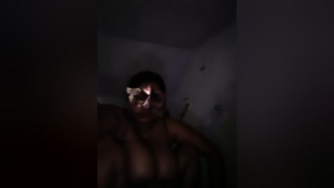 Media: A dimly lit, grainy video of a woman with a bruised and swollen face, sitting in a dark corner, her expression fearful and distressed.