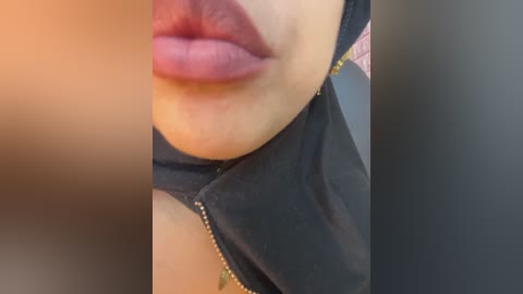 Video of a close-up of a woman's face, showing her full lips painted in a deep red lipstick, and the collar of a black shirt. The background is blurred.