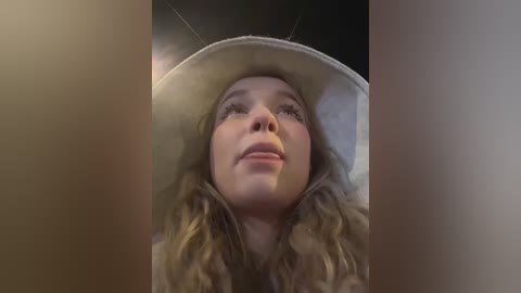 Video of a smiling woman in a white astronaut helmet, with wavy blonde hair visible, taken from a low angle.