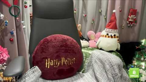 A cozy, festive scene featuring a plush, red \"Harry Potter\" pillow, a white Santa hat, a green and white striped blanket, and Christmas decorations in a well-lit room.