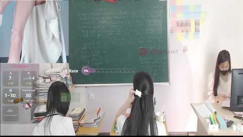 Video of a classroom with a green chalkboard, three students (one Asian female), a teacher, and a virtual reality headset.