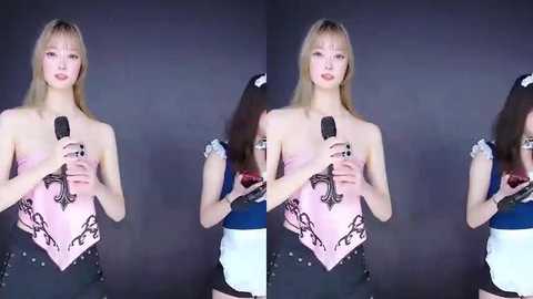 Video of a young, slender, fair-skinned woman with long blonde hair, wearing a pink corset with black lace, standing against a dark background, holding a microphone.