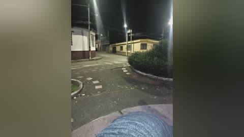 A nighttime video shows a deserted street with a lone person wearing jeans and a blue shirt walking away, illuminated by streetlights. The scene features a yellow building and a white and maroon house.
