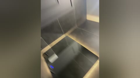 Video of a dark, reflective surface with faint, distorted reflections and blurred shapes, likely from a glass or metal surface, creating a mysterious, abstract composition.