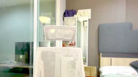 Video of a modern, minimalist hospital room with a white baby bassinet, a flat-screen TV, a blue chair, and a wicker basket.