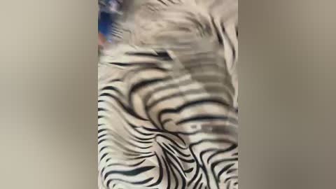 A blurry video showing a person with long, flowing hair in a light color, possibly blonde, against a plain, beige wall. The hair has a wavy, textured appearance.