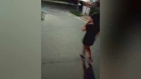 Video of a woman in a black dress running down a suburban street at night, her long hair flowing behind her, blurred motion, and streetlights casting a dim glow.