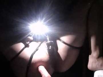 Video of a woman's chest with a bright, starburst light source illuminating her nipple. Her skin is pale, and she wears a black top. The image is intimate and slightly blurred, emphasizing the light's intensity.