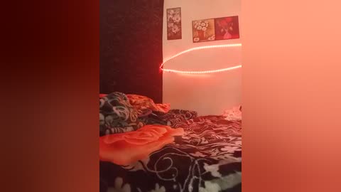 A video of a cozy bedroom with a dark, floral-patterned comforter, a red LED light strip on the wall, and framed art pieces. The room is dimly lit, creating a warm, intimate atmosphere.