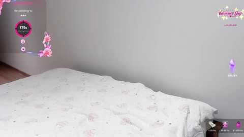 Video of a minimalist bedroom with a white bed, pink floral pillowcases, and a gray wall. A virtual reality headset with a pink and white logo is displayed on the right.