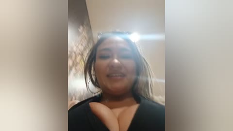 Video of a smiling, young woman with medium brown skin, wearing a black top, captured from a slightly tilted angle.