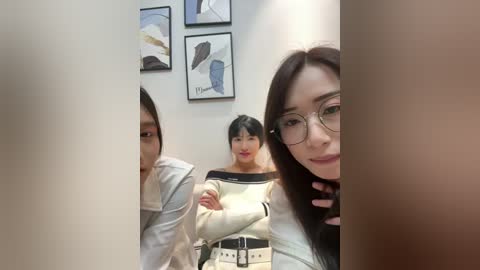 Video of three Asian women in a modern office, featuring minimalist abstract art on the wall and a white desk.