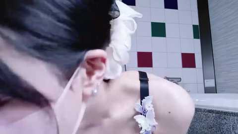 Video of a woman in a white maid outfit, with a black garter belt and lace trim, bending over in a tiled bathroom.