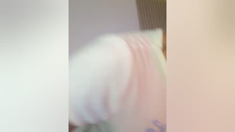 Blurry video of a person, possibly a woman, lying on a bed. The image is out of focus, making it difficult to discern details about the subject's appearance or surroundings.