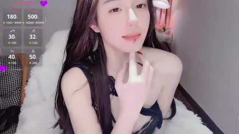 Video of an Asian woman with long black hair, fair skin, and slender physique, posing seductively on a white fur rug. She's wearing a black bra and biting her finger, with a heart overlay and live stream stats in the corner.