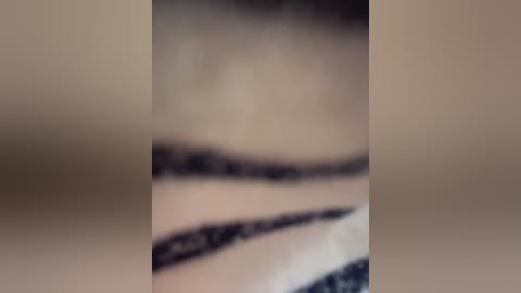 Video of a blurred, close-up shot of a person's leg, likely female, with visible black lace pattern on the thigh. The background is indistinct, possibly indoor, with muted tones.