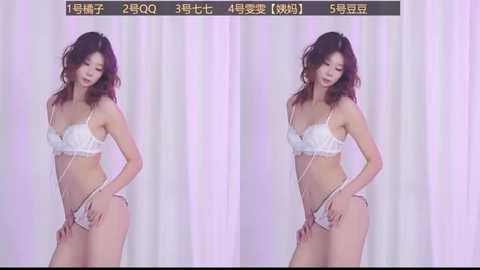 Video of an Asian woman with wavy brown hair, fair skin, and a slender physique, wearing white lace lingerie, standing against white curtains. She has a serene expression, looking down slightly.