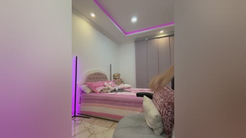 Video of a modern bedroom with a plush, pink bed, pink and white quilted bedding, a tufted headboard, and a purple mood light.