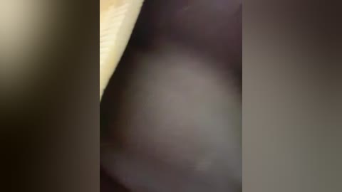 This is a blurred video with a dark background and a faintly visible light source in the top left corner. The image appears to show a close-up of a person's face or part of their body, with indistinct features due to the lack of clarity.