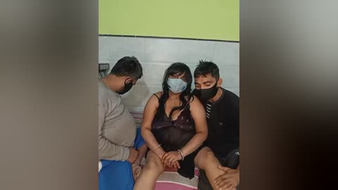 Video of three people in a public restroom; a woman in a revealing purple lingerie, two men in casual clothes, wearing masks.