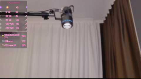 Video of a modern, well-lit room with a white ceiling and beige curtains. A large, powerful light fixture with a blue LED strip hangs from the ceiling, illuminating the space.