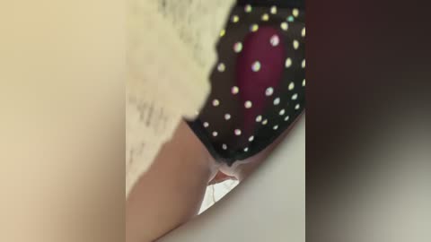 Video of a close-up of a woman's lower torso, showing white lace panties with a black polka dot pattern and a maroon thong peeking out.