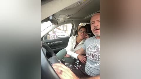 Media: A candid video captures a man and woman in a car, with the woman leaning into the man, who is wearing glasses and a gray shirt.