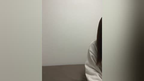 Media: A video showing a person's hand, partially covered by a white shirt sleeve, holding a knife against a plain, light-colored wall. The image has a minimalistic, somewhat tense atmosphere.