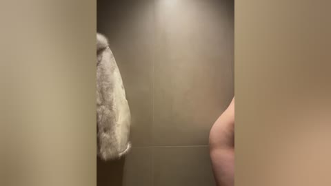 Video of a close-up of a furry, light brown stuffed animal hanging in a beige cubicle, viewed through a partially open door.