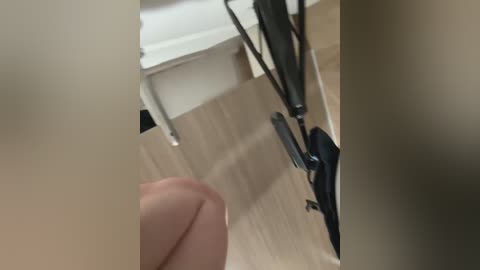 A close-up video of a person's hand, holding a black vacuum cleaner cord, in a modern, beige-toned bathroom with a white toilet visible in the background.