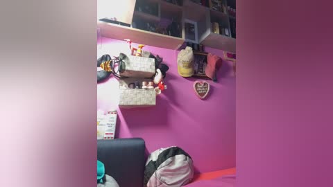 A video of a colorful, cluttered room with pink walls and shelves holding stuffed animals, baskets, and a heart-shaped sign. A black chair is partially visible on the left.