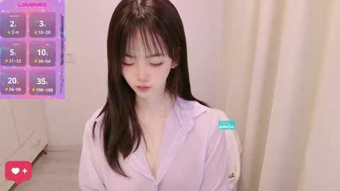 Media: A video of a young Asian woman with long black hair, fair skin, and a slender build, wearing a white button-up shirt, sitting in a room with a white curtain and a purple background, indicating a livestream.