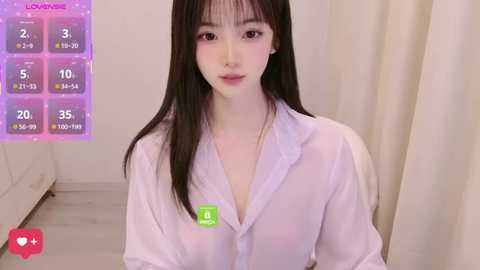 Media: A video of a young East Asian woman with long black hair, pale skin, and a slender physique, wearing a white shirt. She stands against a beige curtain in a minimalist room.