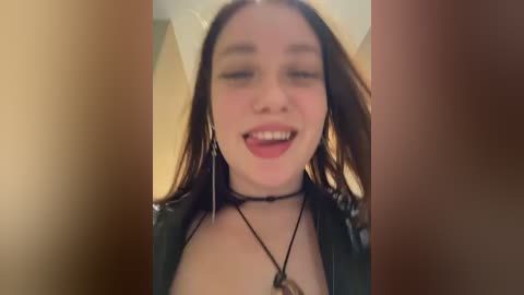 Media: A video of a young woman with long dark hair, wearing a black leather jacket and a choker necklace, smiling widely, with blurred figures in the foreground.