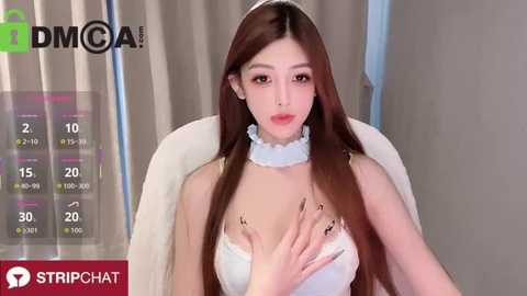 Media: Video of an East Asian woman with long, straight brown hair, fair skin, and small breasts, wearing a white, frilly, low-cut top, sitting on a white chair. Background shows a beige curtain.