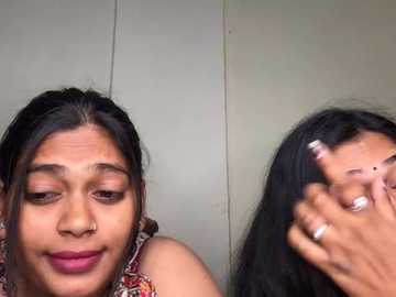 Video of a South Asian woman with medium brown skin and long black hair, smiling. She wears a colorful scarf and a nose ring. The background is plain beige.