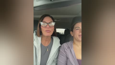 Video of two women in a car, one with glasses and light hair, another with a hat and dark hair.