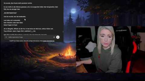 Video of a young blonde woman in glasses, wearing a green sweater, speaking on a video call while a campfire burns in a forested background.