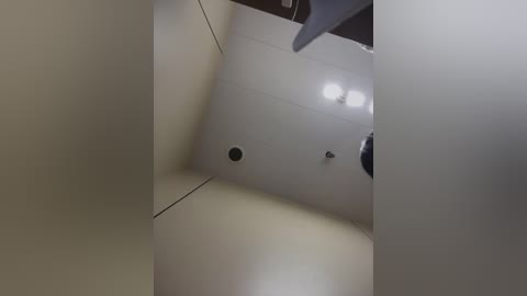 Video of a modern, dimly lit room with a white ceiling, two recessed lights, and a black door frame, giving an angular, slightly distorted perspective.