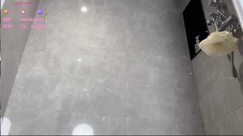 Video of a modern bathroom with white, glossy marble tiles. A large, fluffy white towel hangs on the wall. Bright, pink text overlays the image, likely from a video recording app.