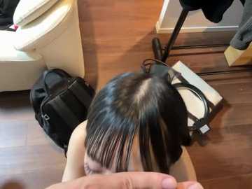 Video of a woman with long, straight black hair, wearing a black top, kneeling on a wooden floor, with a black backpack nearby.