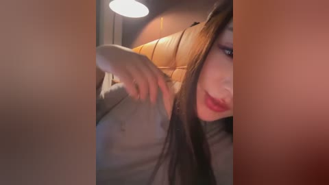 A video showing a woman with long, dark hair and red lipstick, combing her hair in a dimly-lit car interior, featuring a beige headrest and soft lighting.