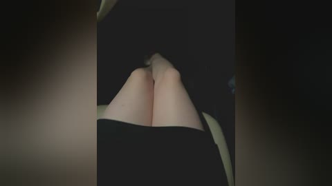 Video of a close-up, dimly lit view of a person's bare legs and feet, with a dark background, suggesting a seductive or intimate setting.