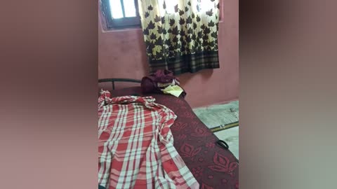 Video of a simple, sparsely furnished bedroom with a single bed, red and white plaid sheet, and a dark curtain with a star pattern.