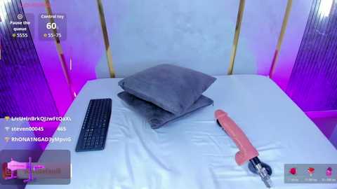 A video of a modern bedroom with a white bed, gray pillows, and a pink vibrator on the sheets. The room is lit with purple ambient lighting.